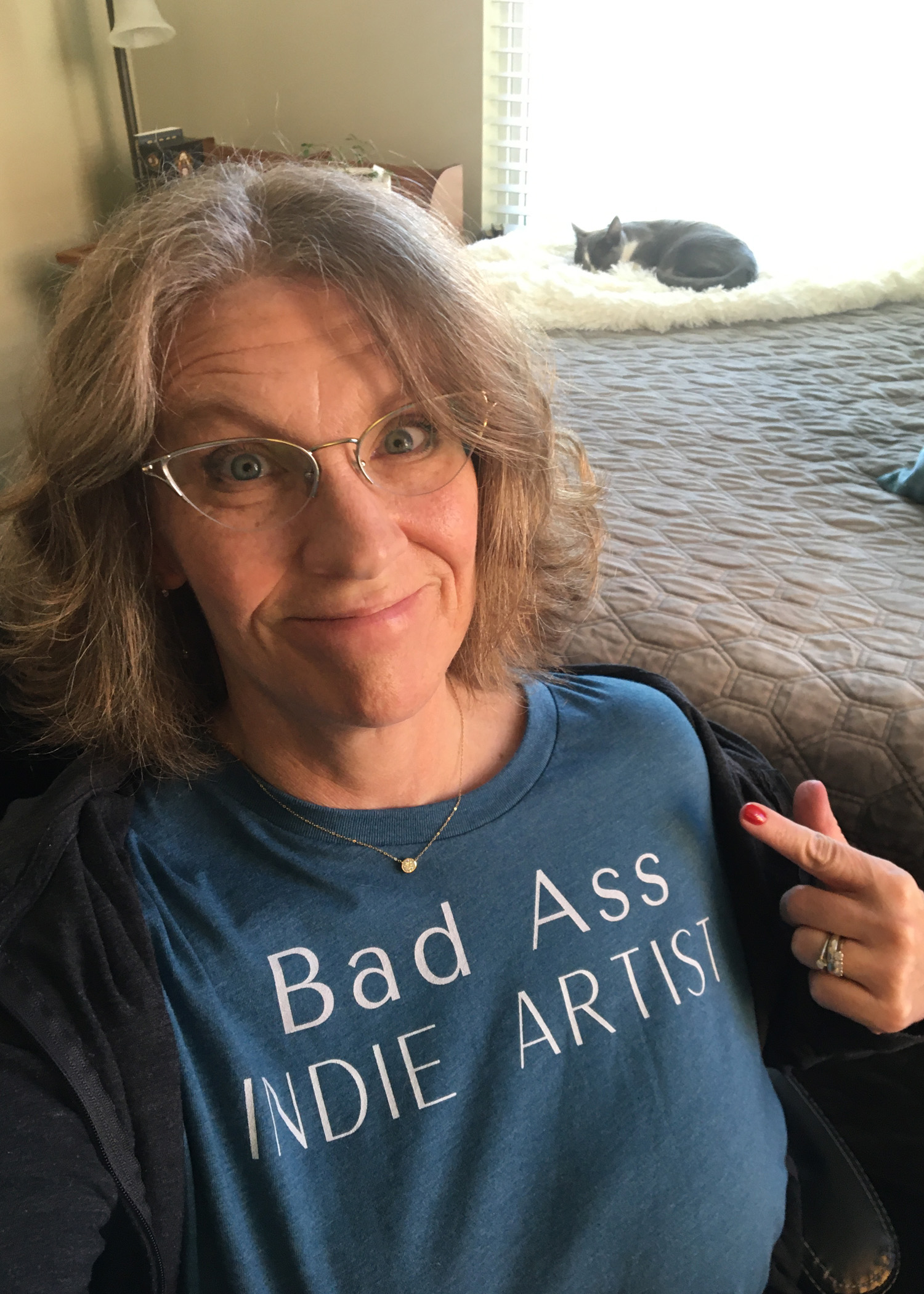 Pointing to text on t-shirt 'Bad Ass Indie Artist".